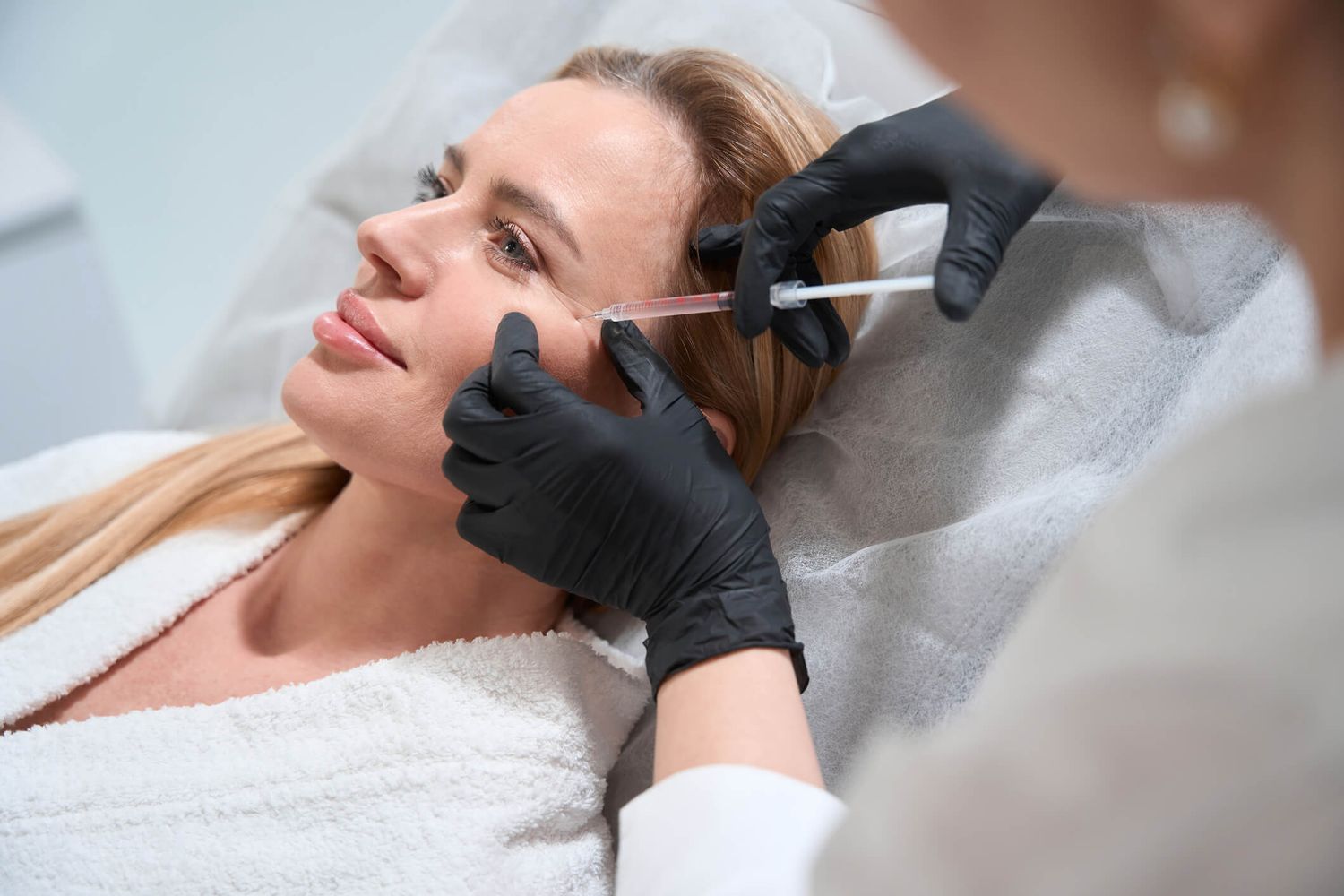 Matt Azulay-LaFever and a student model injecting dermal filler into the chin of a patient model