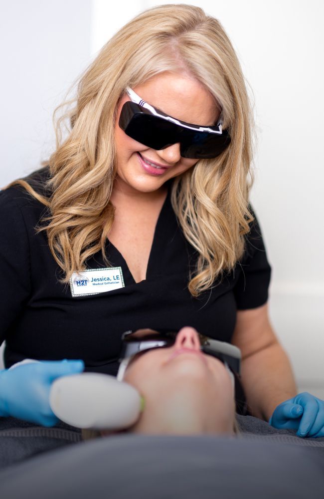 aesthetic training student model smiling down at a patient model laying back in a chair