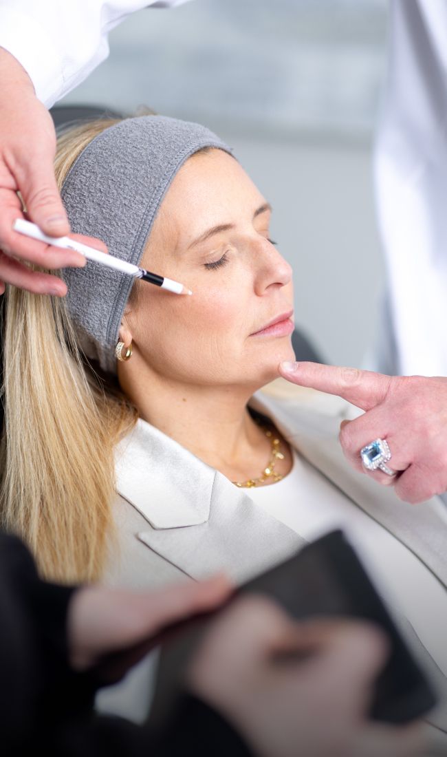 aesthetic training student model marking a patient model's cheeks