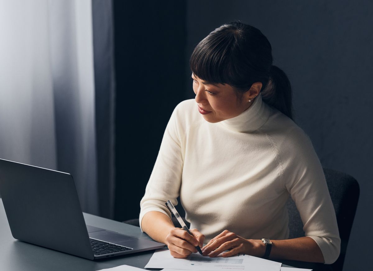 laser certification student looking at her laptop and making notes on paper